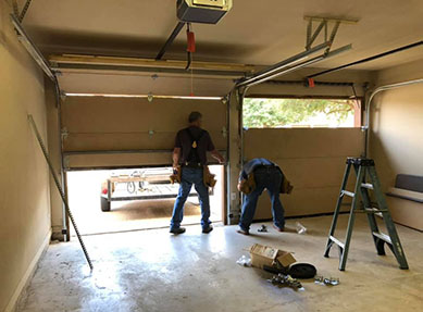 A modern garage door with a sleek design, featuring horizontal panels in a dark color, installed on a contemporary home with a light-colored exterior.